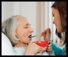 Caretaker feeding older woman