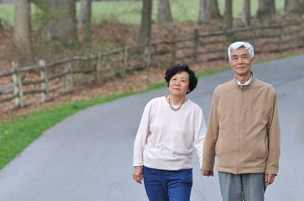 Senior couple hand in hand walking on country road